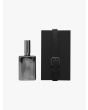 Front of the silver-tone glass bottle of Goti Earth perfume and black box with strap.